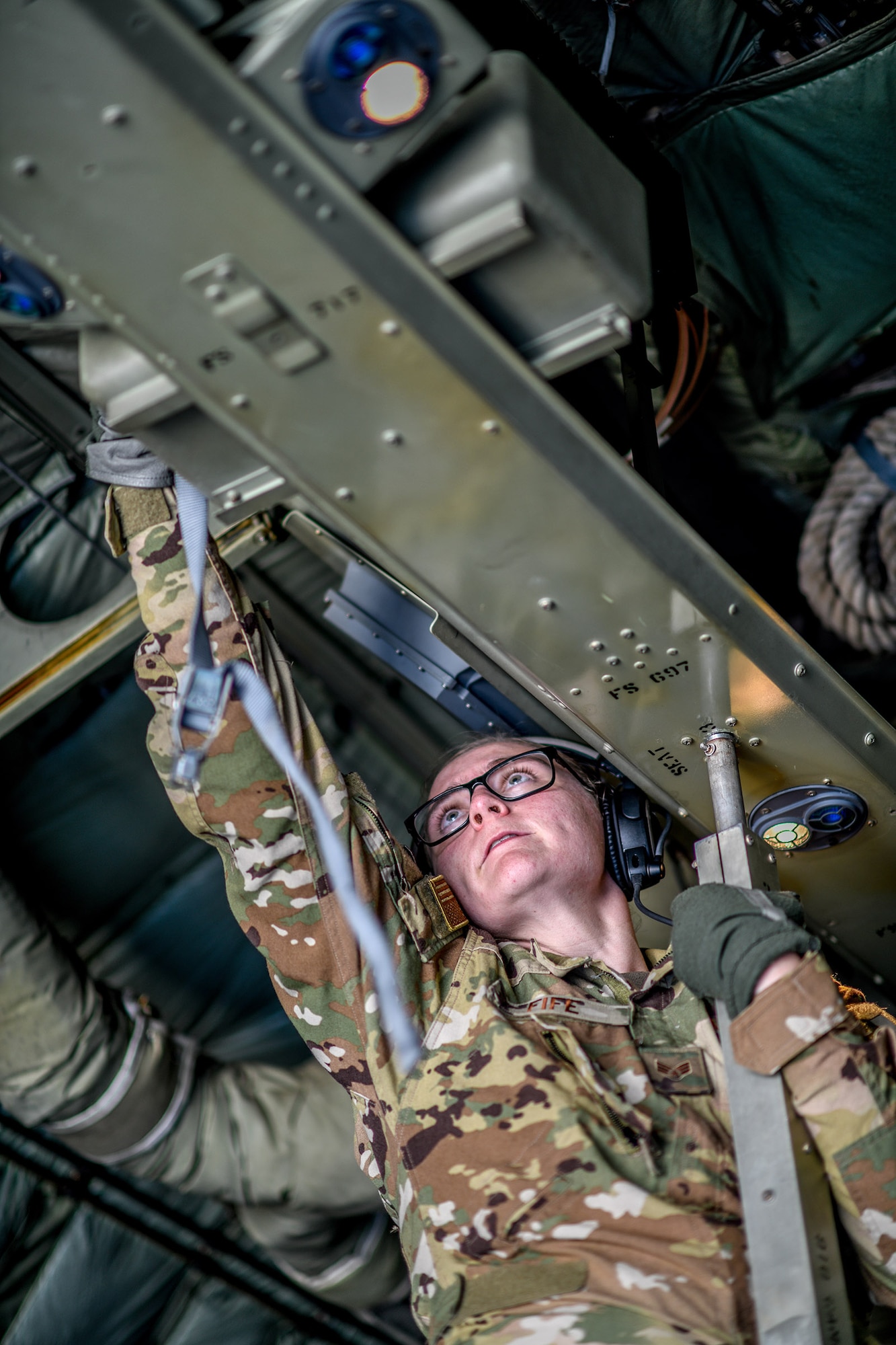 A Reserve Citizen Airman with the 445th Aeromedical Evacuation Squadron reaches up to connect cargo straps aboard a Youngstown Air Reserve Station C-130H Hercules aircraft on July 10, 2019, on the flightline at Wright-Patterson Air Force Base.