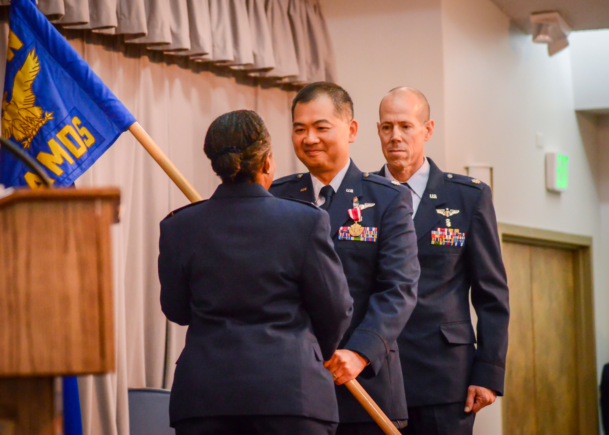 Lt. Col. Vinh Tran, the outgoing 412th Aerospace Medicine Squadron Commander, hands the unit guidon back to Col. Gwendolyn Foster, 412th Medical Group Commander, during an inactivation and redesignation ceremony at Edwards Air Force Base, July 12. Tran relinquished his command to Lt. Col. Arthur Lawrance, the 412th AMDS was then redesignated into the 412th Operational Medical Readiness Squadron.