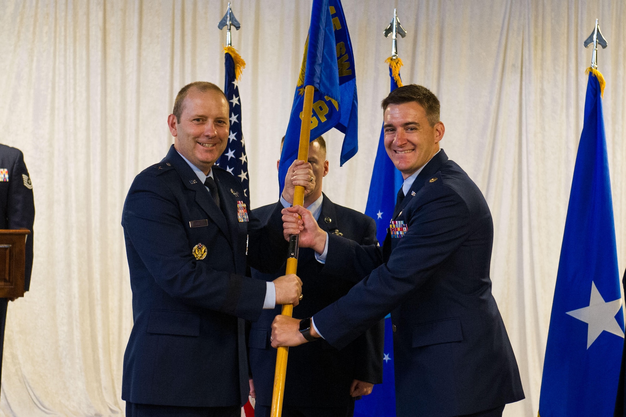 Brig. Gen. Douglas Schiess, 45th Space Wing commander, presents Maj Christopher James, incoming 45th Comptroller Squadron commander, with the 45th CPTS guidon as he assumes command of the squadron. (U.S. Air Force photo by Amanda Ryrholm)