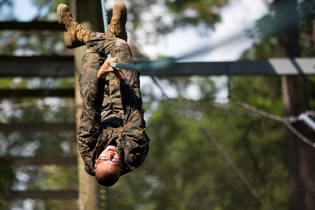 A Marine Corps recruit climbs across an obstacle.