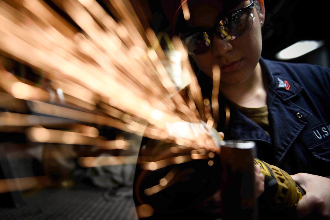 A sailor uses a torch on metal.