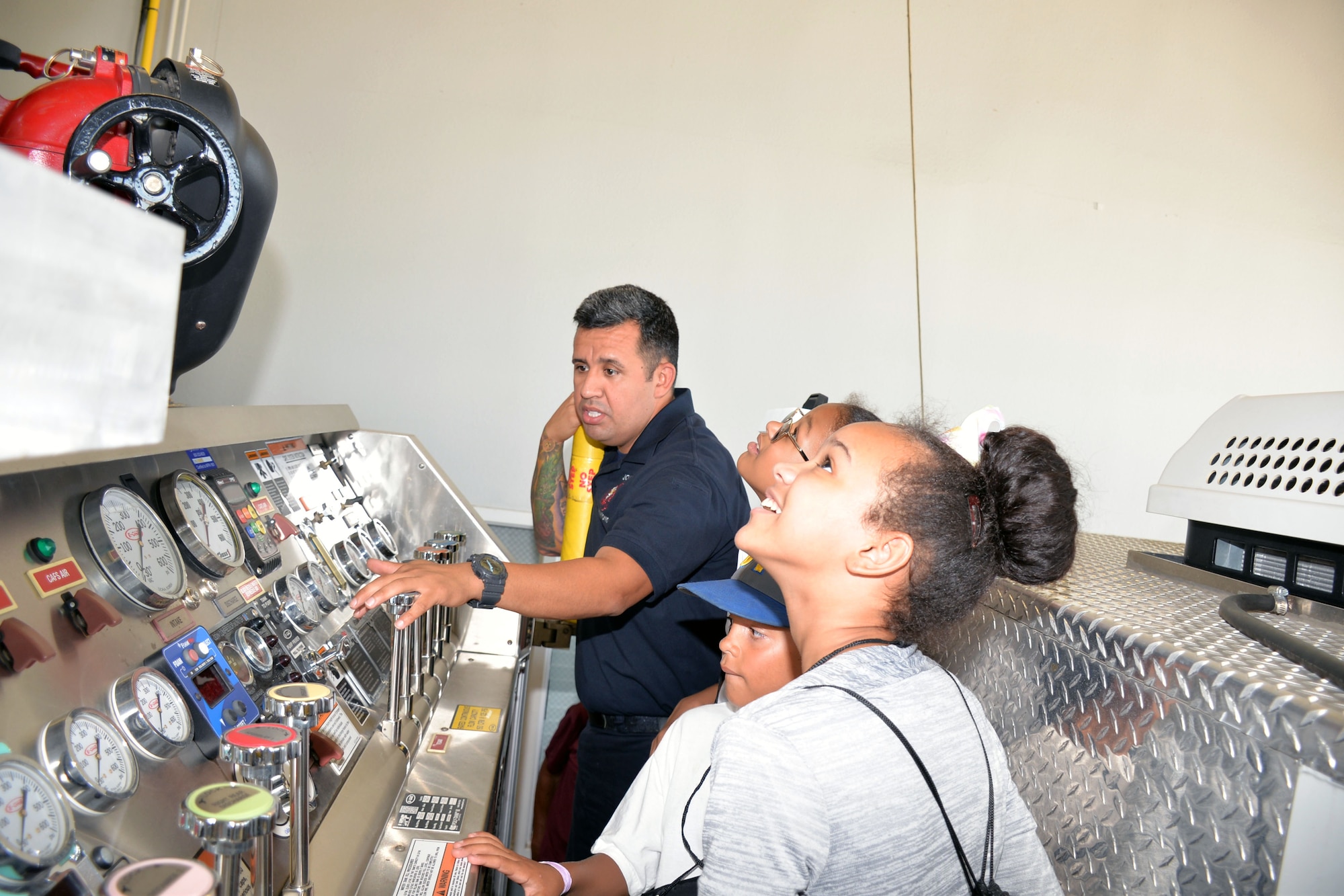 Mike Vigil, 802nd Civil Engineer Squadron firefighter, explains the controls for a fire engine to students with the San Antonio Chapter of Tuskegee Airmen Inc.’s Youth Science, Technology, Engineering and Mathematics-Aviation Program during a tour of Fire Station #1 July 12, 2019 at Joint Base San Antonio-Lackland, Texas.