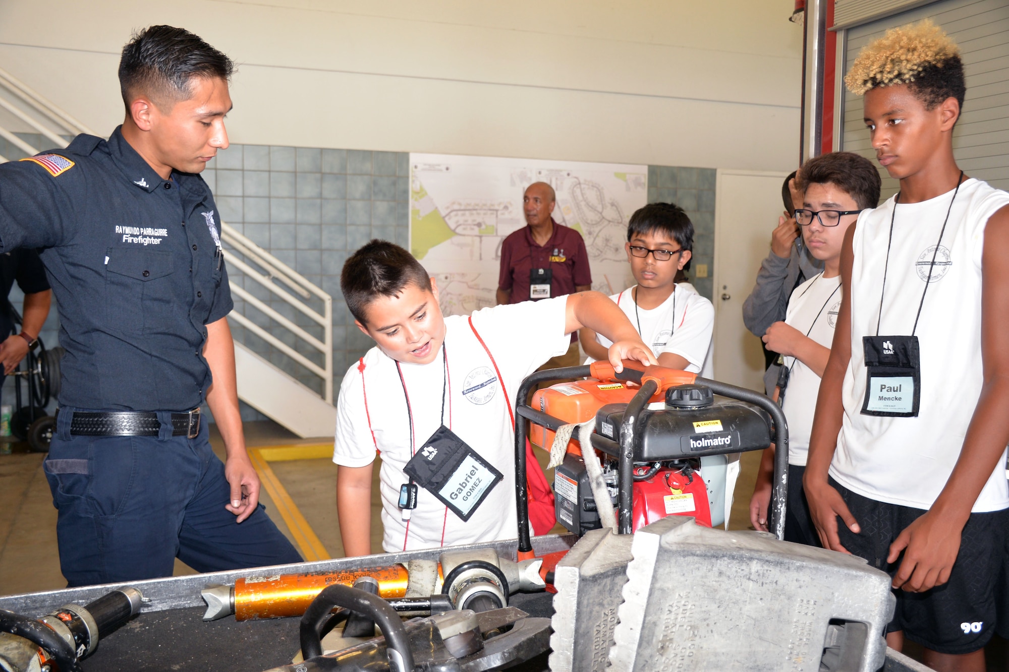 Raymundo Parraguirre, 802nd Civil Engineer Squadron firefighter, talks with students with the San Antonio Chapter of Tuskegee Airmen Inc.’s Youth Science, Technology, Engineering and Mathematics-Aviation Program about firefighter tools during a tour of Fire Station #1 July 12, 2019 at Joint Base San Antonio-Lackland, Texas.