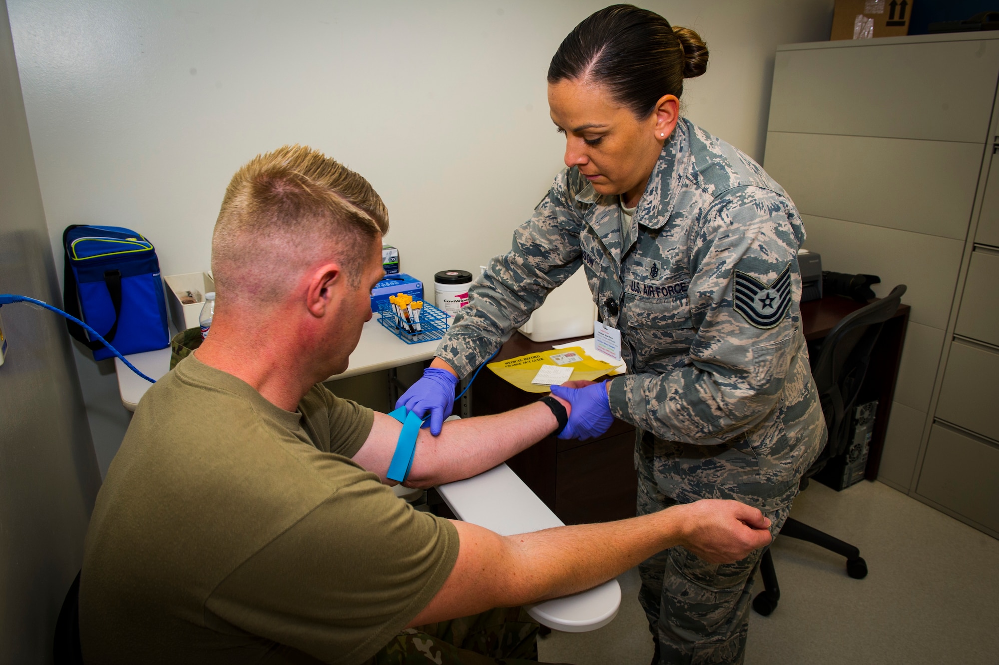 U.S. Air Force Tech Sgt. Leslie Robinson, 926th Aerospace Medicine Squadron medical lab technician, preps Master Sgt. Nicholas Hicks, 926th Aircraft Maintenance Squadron viper aircraft maintenance unit flight chief, to have blood drawn inside the medical clinic at Nellis Air Force Base, Nevada, July 13, 2019. The 926th AMDS provides flight medical support and medical manpower to accomplish the Reserve Component Physical Health Assessment Process for the wing population to ensure units’ medical requirements for deployment are met.. The 926 AMDS works cohesively to ensure all reserve personnel assigned are medically and operationally ready to fulfill the wing’s mission. (U.S. Air Force photo by Senior Airman Brett Clashman)