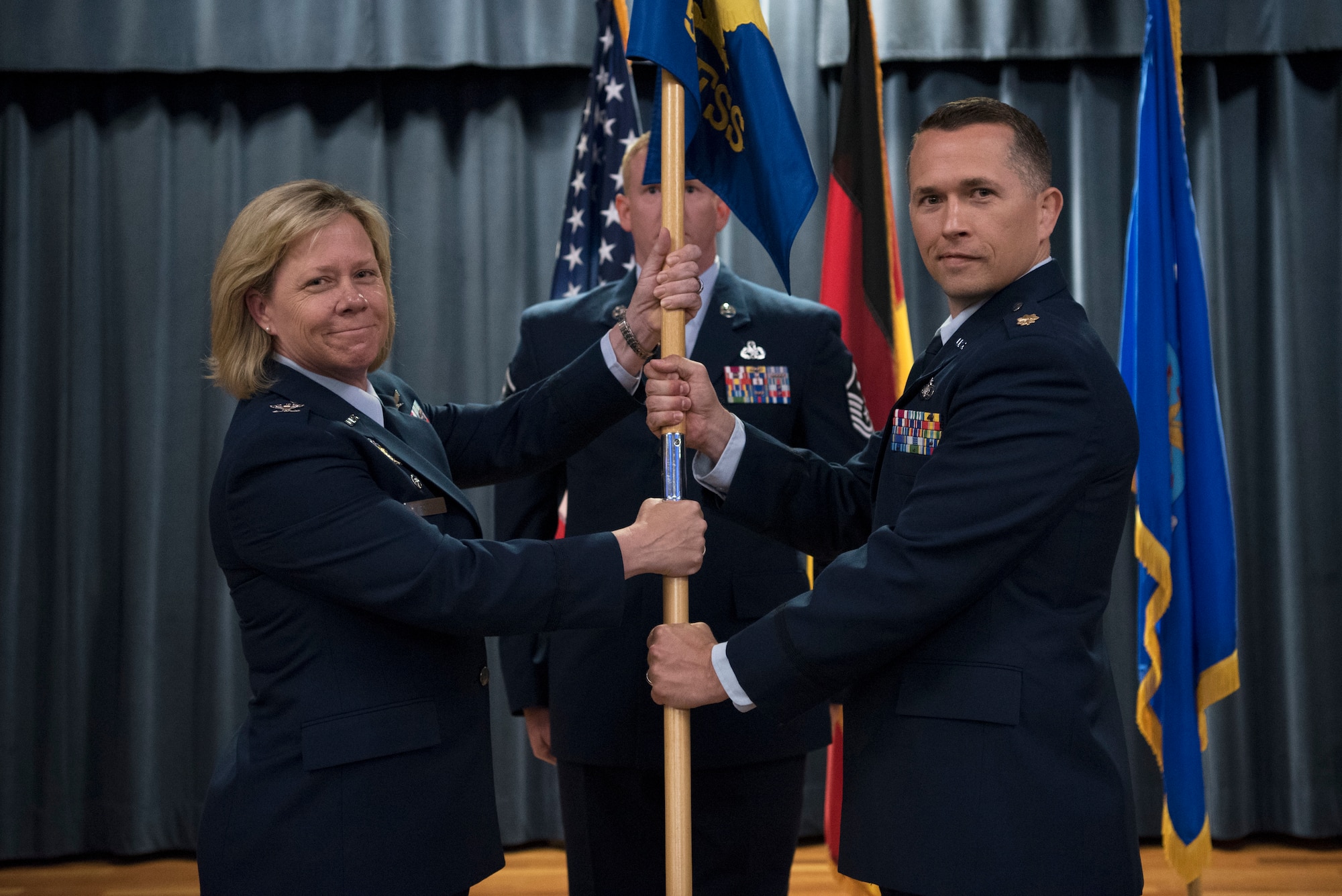 U.S. Air Force Col. Marlyce Roth, 52nd Mission Support Group commander, left, passes the ceremonial guidon to U.S. Air Force Maj. Adam Baker, incoming Force Support Squadron commander, right, during a change of command ceremony at Spangdahlem Air Base, Germany, July 15, 2019.