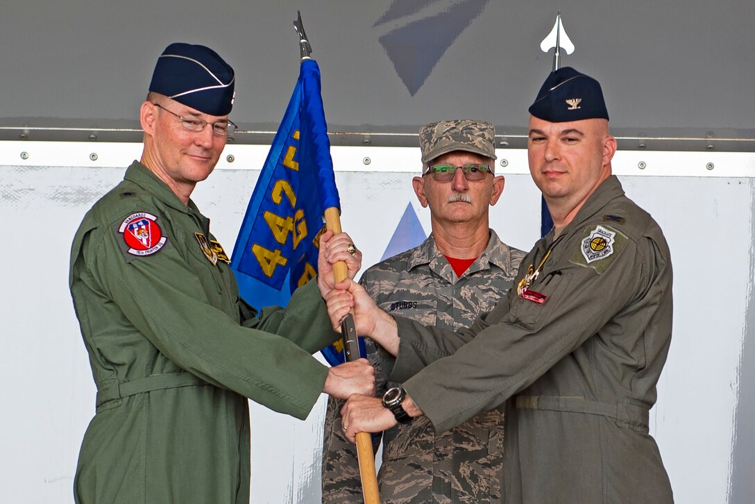 Brig. Gen. Rogers Suro, left, 442d Fighter Wing commander, receives the guidon from Col. Gerald Cook, 476th Fighter Group (FG) commander, right, as he relinquishes command during the 476th FG change of command ceremony, July 9, 2019, at Moody Air Force Base (AFB), Ga. Cook is a command pilot with more than 3,200 flying hours. (U.S. Air Force photo by Airman Azaria E. Foster)