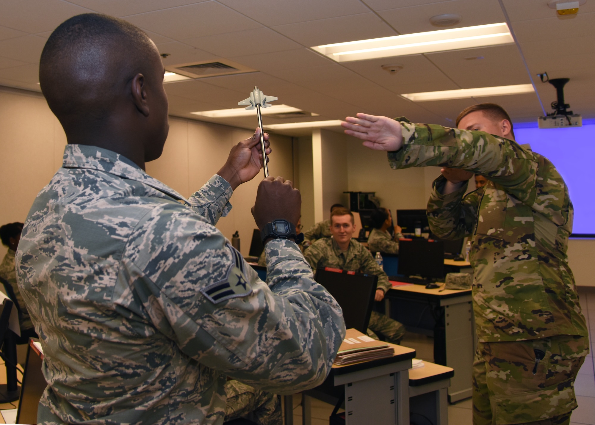 U.S. Air Force Staff Sgt. Zachary Moore, 315th Training Squadron instructor, suggests a conceivable threat to the flight path of Airman 1st Class James Bullock’s, 315th TRS student, F-35 Lightning II aircraft prop in Di Tommaso Hall on Goodfellow Air Force Base, Texas, July 10, 2019. Critical thinking skills are paired with hands-on maneuvers to help the intelligence students identify, analyze and recommend counter tactics in order to offer future intelligence training for air crews in the operational Air Force. (U.S. Air Force photo by Airman 1st Class Abbey Rieves/Released)