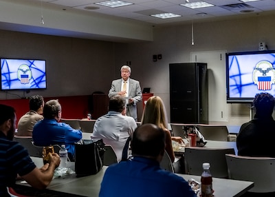 Defense Logistics Agency Land and Maritime acting Deputy Commander and Acquisition Executive speaking to group of DLA Land and Maritime Associates in a conference room.