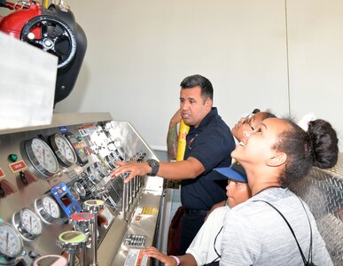 Mike Vigil, 802nd Civil Engineer Squadron firefighter, explains the controls for a fire engine to students with the San Antonio Chapter of Tuskegee Airmen Inc.’s Youth Science, Technology, Engineering and Mathematics-Aviation Program during a tour of Fire Station No. 1 at Joint Base San Antonio-Lackland July 12.