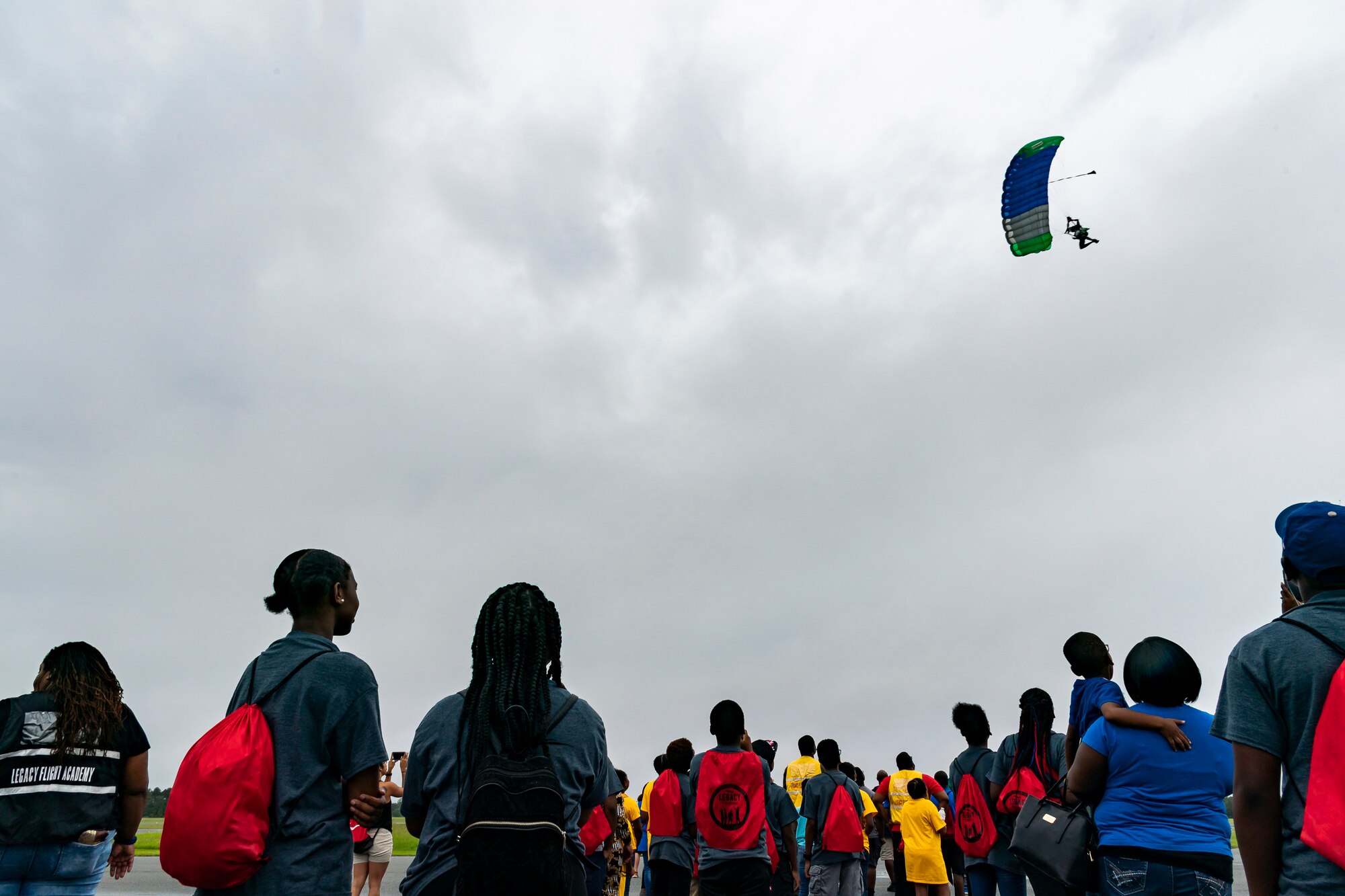 Participants watch a skydiver during the Eyes Above the Horizon diversity outreach program, July 13, 2019, in Valdosta, Ga. The Valdosta Regional Airport hosted the Legacy Flight Academy and over 60 youths ranging in age from 10-19 for a day of flight introduction and immersion into the legacy of the historic Tuskegee Airmen. The program is designed to remove barriers for underrepresented minorities and inspire an interest in aerospace careers. (U.S. Air Force photo by Airman 1st Class Hayden Legg)
