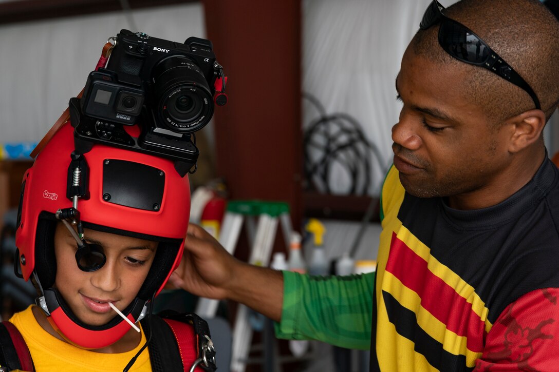 Nicholas Walker, right, Team Blackstar Skydivers Demonstration Team member, puts his helmet on a participant during the Eyes Above the Horizon diversity outreach program, July 13, 2019, in Valdosta, Ga. The Valdosta Regional Airport hosted the Legacy Flight Academy and over 60 youths ranging in age from 10-19 for a day of flight introduction and immersion into the legacy of the historic Tuskegee Airmen. The program is designed to remove barriers for underrepresented minorities and inspire an interest in aerospace careers. (U.S. Air Force photo by Airman 1st Class Hayden Legg)