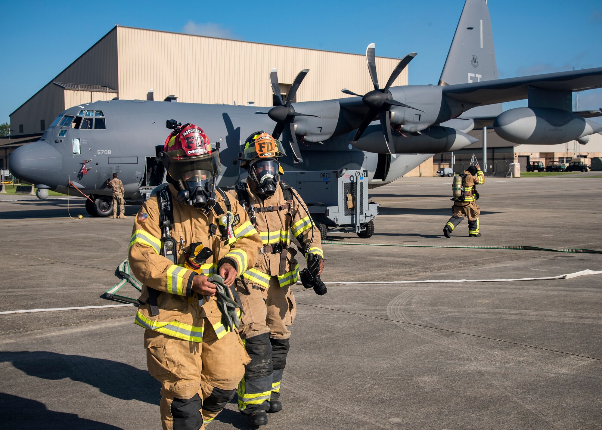 Firefighters from the 23d Civil Engineer Squadron (CES), take off their personal protective gear following HC-130J Combat King II egress training, July 11, 2019, at Moody Air Force Base, Ga. Firefighters conducted the training to evaluate their overall knowledge and proficiency of how to properly shut down and rescue personnel from a C-130 during an emergency situation. The training required the firefighters to properly enter and ventilate the aircraft while conducting swift rescue techniques to safely locate and remove passengers from the aircraft. (U.S. Air Force photo by Airman 1st Class Eugene Oliver)