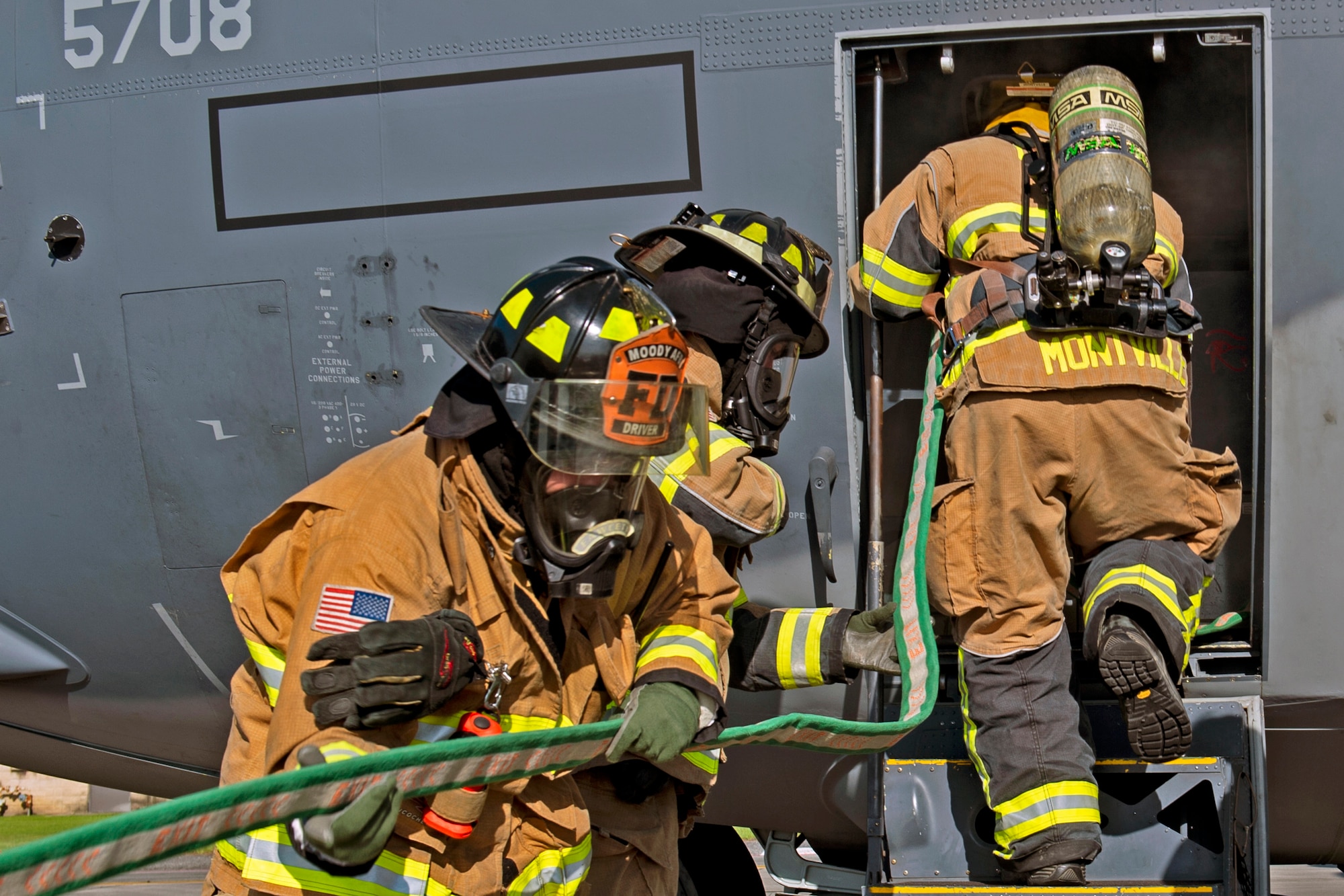 Firefighters from the 23d Civil Engineering Squadron (CES) carry a hose during an HC-130J Combat King II egress training, July 11, 2019, on Moody Air Force Base, Ga. The 23d CES conducted the exercise to simulate the rescue of victims from a smoking C-130. The firefighters were tasked with locating and providing ventilation within the aircraft to safely remove the victims. (U.S. Air Force photo by Airman Azaria E. Foster)