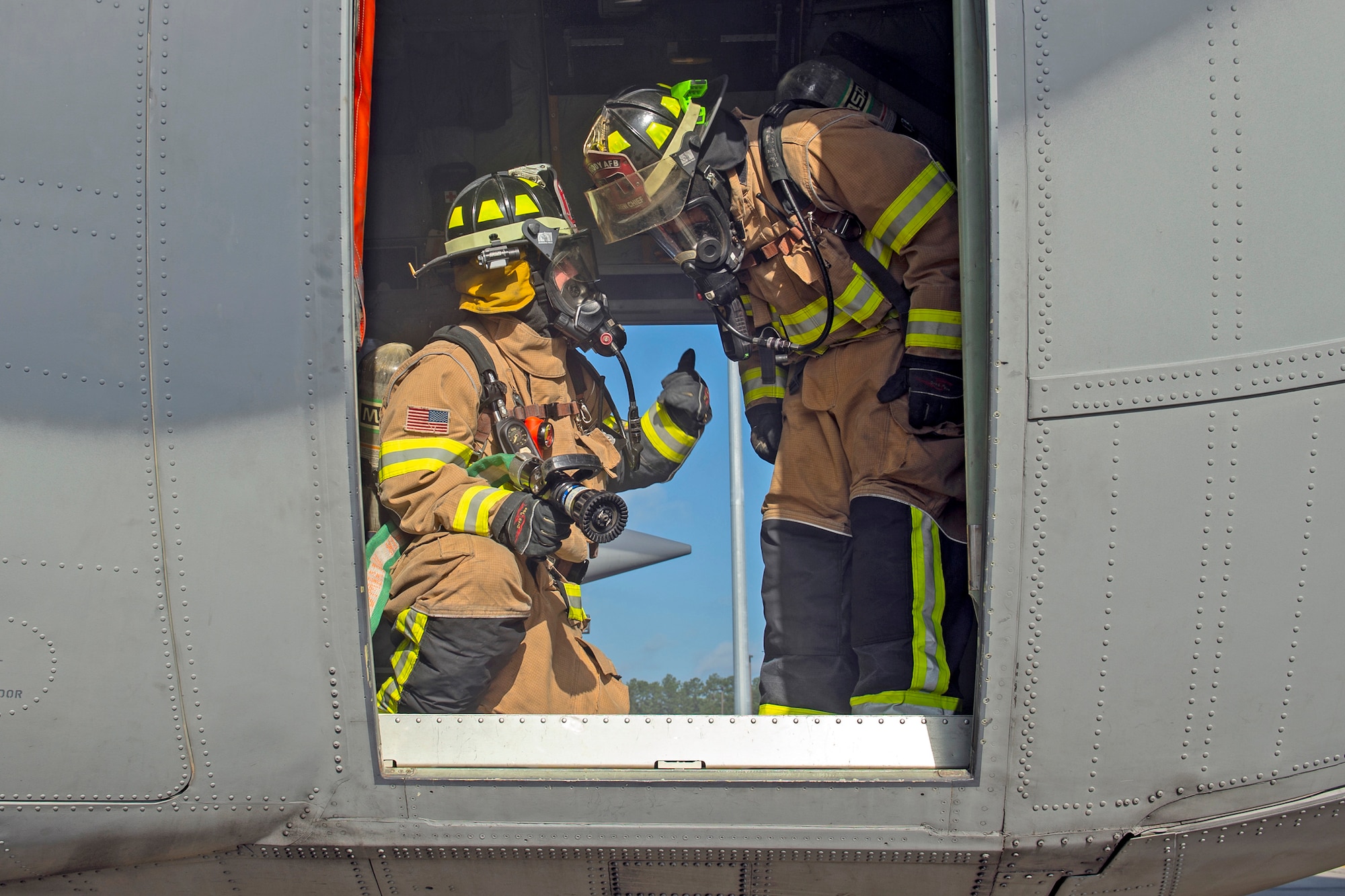 Staff Sgt. Matthew Montville, left, gives a thumbs up to Staff Sgt. Tyler McFarland, right, both 23d Civil Engineering Squadron firefighter crew chiefs, during an HC-130J Combat King II egress training, July 11, 2019, on Moody Air Force Base, Ga. The 23d CES conducted the exercise to simulate the rescue of victims from a smoking C-130. The firefighters were tasked with locating and providing ventilation within the aircraft to safely remove the victims. (U.S. Air Force photo by Airman Azaria E. Foster)