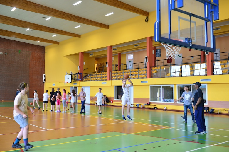 A student shoots a basketball during a community outreach day event near Powidz Air Base, Poland, July 13, 2019. Volunteers and students worked together to overcome language barriers while learning to play basketball. (U.S. Air Force photo by Staff Sgt. Jimmie D. Pike)