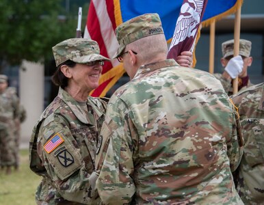 U.S. Army Brig. Gen. Jeffrey Johnson (right), Regional Health Command-Central commanding general, presents the guideon to U.S. Army Brig. Gen. Wendy L. Harter (left), Brooke Army Medical Center commanding general, at a change of command ceremony at Joint Base San Antonio-Fort Sam Houston July 16. Harter is BAMC’s first female commanding general.