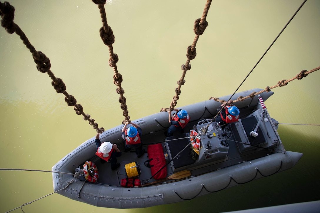 A group of sailors hover over water in an inflatable craft.