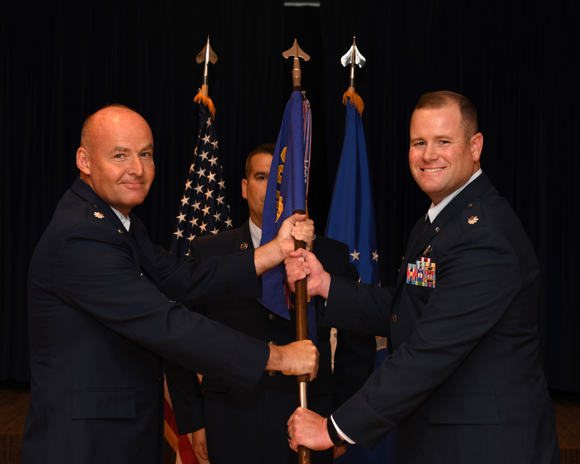 Lt. Col. John Goodman, 690th Cyberspace Operations Group deputy commander, presents the guidon to Lt. Col. Joshua Diehl, the new 561st Network Operations Squadron commander, during a change of command ceremony July 16, 2019 on Peterson Air Force Base, Colorado. Passing the guidon is a formal tradition that symbolizes the transfer of command from the outgoing to the incoming commander, ensuring that the unit is never without leadership. (U.S. Air Force photo by Airman 1st Class Andrew J. Bertain)