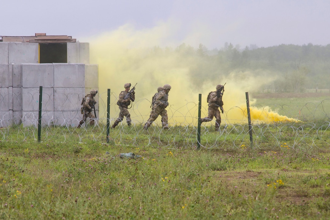 Four soldiers run with weapons with yellow smoke in the background.