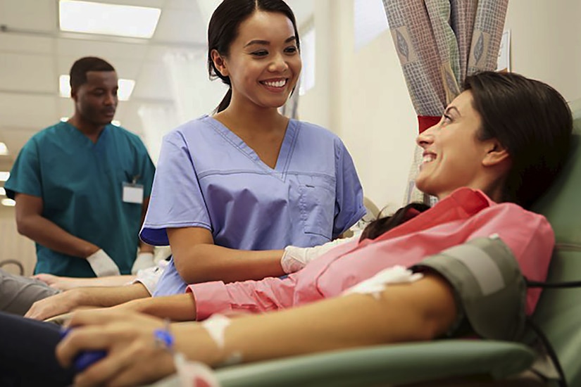 Health care provider checks on woman in hospital bed.