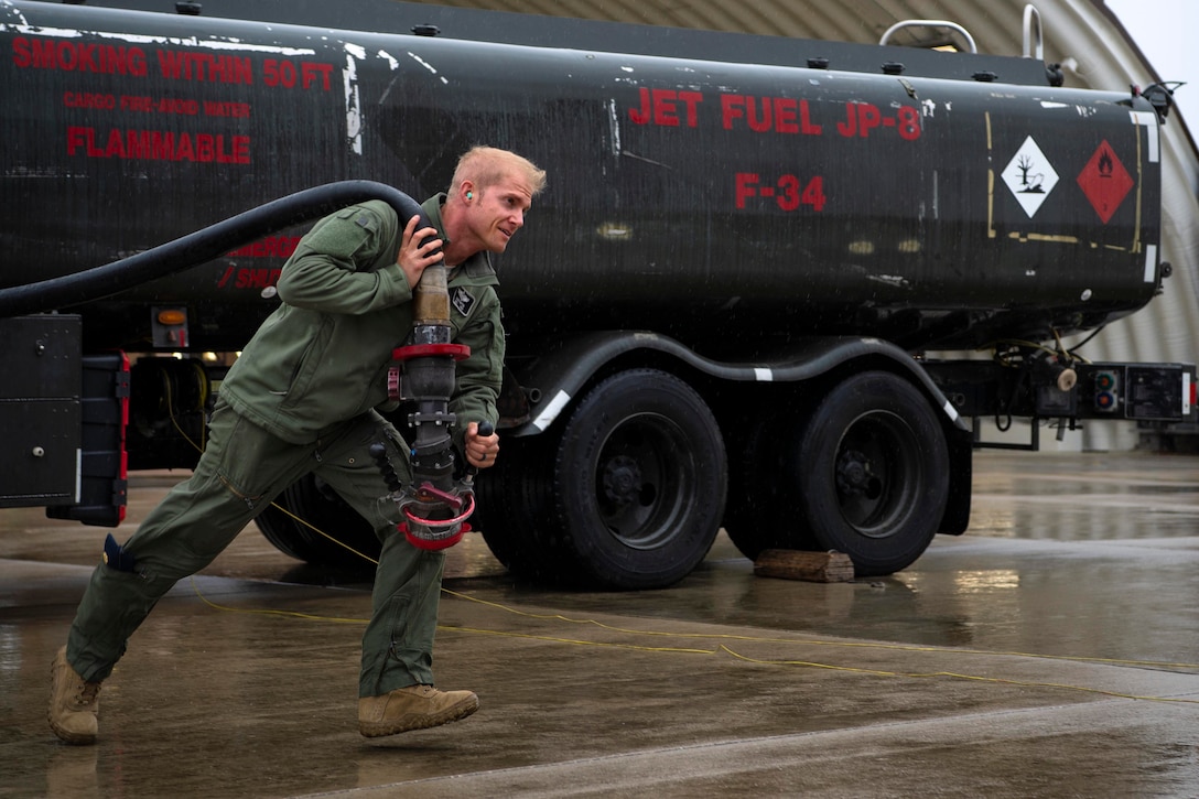 An airman drags a hose over his shoulder.