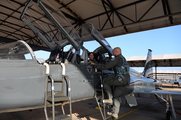 Maj. Saily Rodriguez, the Human Systems Program Office female fitment program manager, sits in a T-38 Talon while Maj. Ryan Claussen, 50th Flying Training Wing chief of instructor pilots, climbs a ladder, July 12, 2019, on Columbus Air Force Base, Mississippi. Rodriguez went on the incentive flight to test the equipment and to try out a disposable urinary relief device called the Traveljohn.