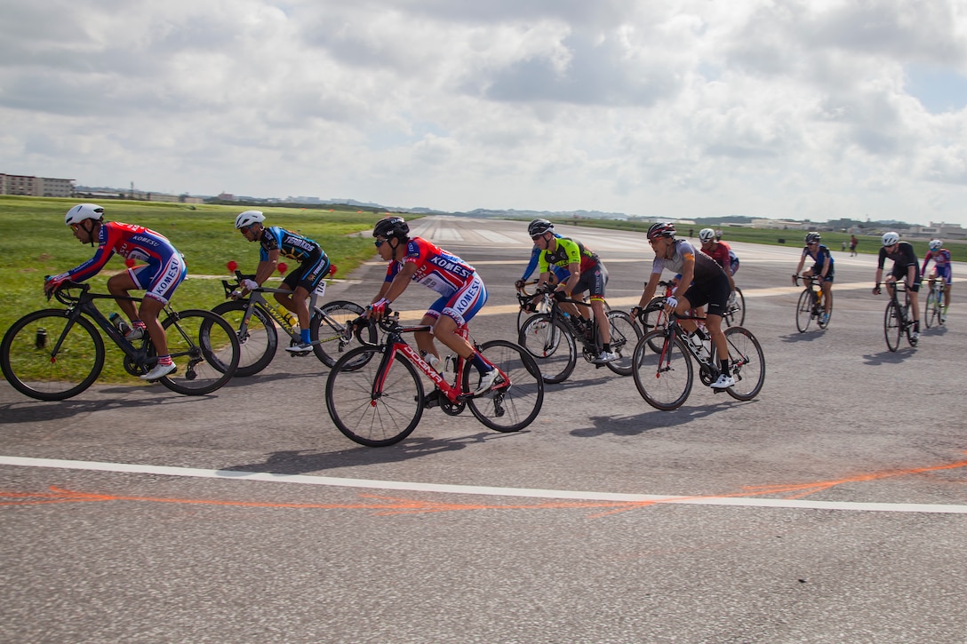 Cyclists race against one another on Marine Corps Air Station Futenma, Okinawa, Japan, July 14, 2019. Cyclists were racing the 2019 Futenma Bike Race; a competition that invites Status of Forces Agreement personnel and the local Okinawan community to compete on and around MCAS Futenma’s airfield. (U.S. Marine Corps photo by Cpl. Christopher A. Madero) (U.S. Marine Corps photo by Cpl. Christopher A. Madero)