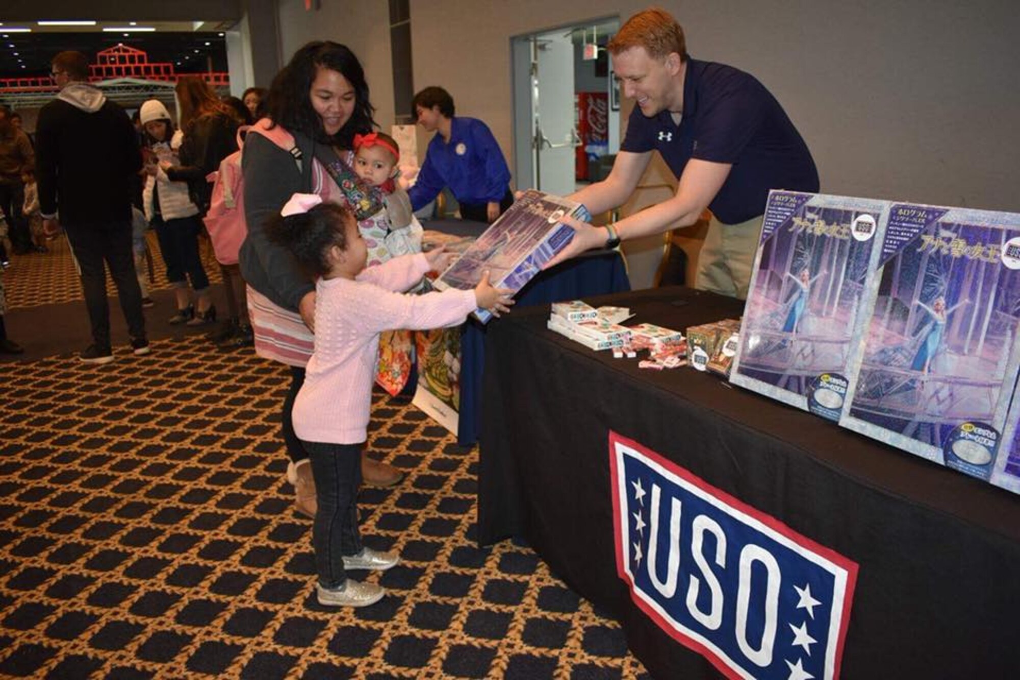 Nathan Evans, United Service Organizations field program manager, gifts a present to a young girl at a USO holiday event at Yokota Air Base, Japan, Dec. 10, 2017.