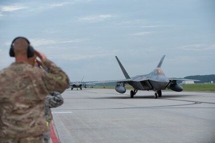 Maintainers and senior leaderships from the 1st Fighter Wing salute F-22 Raptors from the 1st Fighter Wing, 27th Fighter Squadron as the taxi to take-off during a deployment to Al Udeid Air Base, Qatar, from Joint Base Langley-Eustis, Virginia. The F-22's deployed to Qatar for the first time in order to defend American forces and interests in the U.S. Central Command area of responsibility. (U.S. Air Force Photo by Staff Sgt. Kaylee Dubois)
