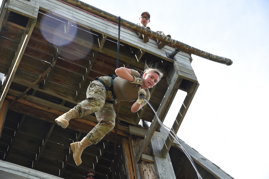Airman 1st Class Maggie Hebert, of the 219th Security Forces Squadron lowers herself on a rope using an ‘Australian Reppel’ method, as instructor Staff Sgt. Jon Rambow, of the 817th Engineer Company, shouts directions to her from above at the Camp Gilbert C. Grafton Training Center, near Devils Lake, N.D., July 16, 2019. Hebert is learning new skills and honing and refining practices she has already learned during the annual training period at Camp Grafton.