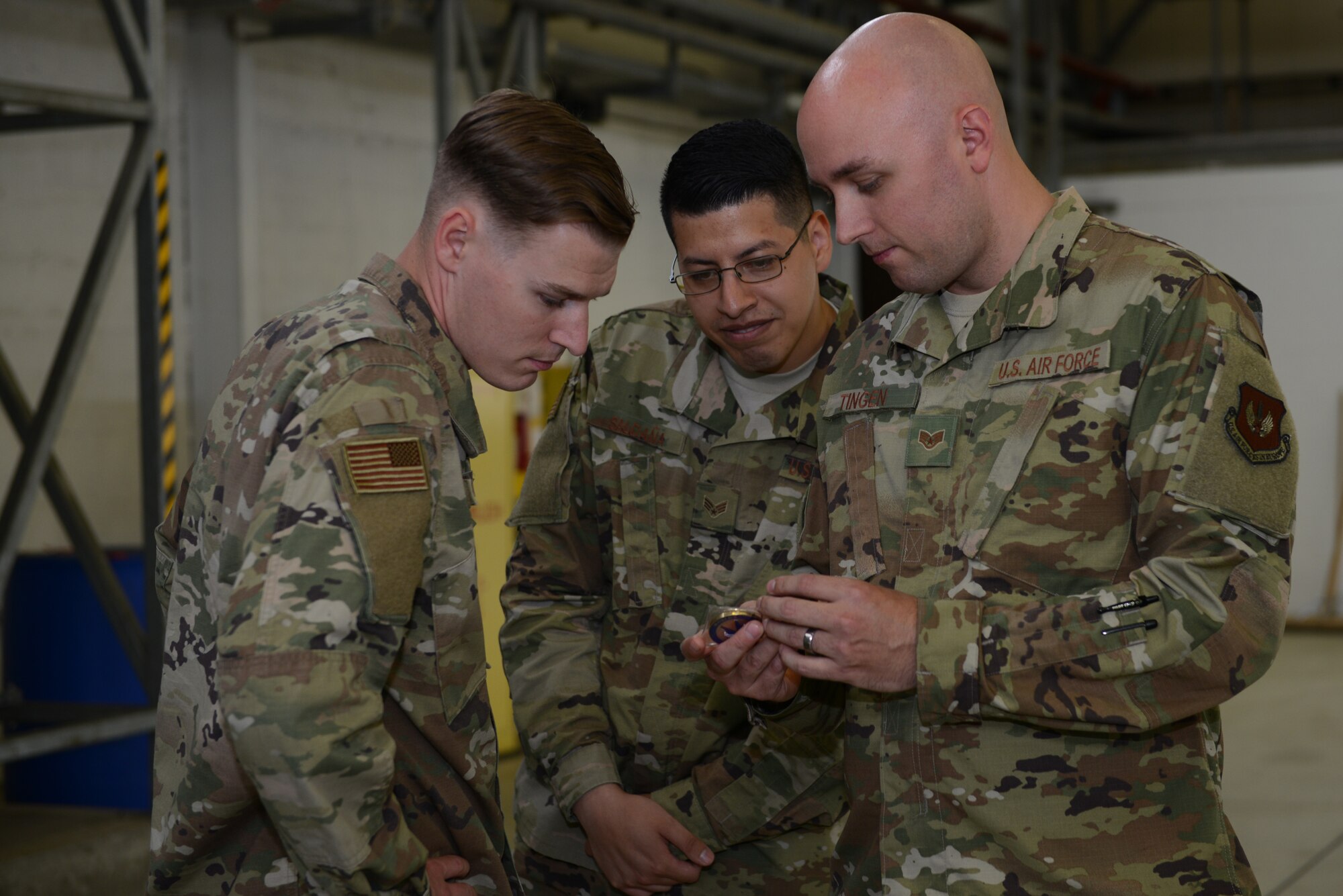 U.S. Air Force Staff Sgt. Zachary Tingen, 86th Maintenance Squadron aircraft fuel systems craftsman, shows a coin to his colleagues on Ramstein Air Base, Germany, July 15, 2019. Tingen received the coin just minutes prior for leading his team through cross utilization training.