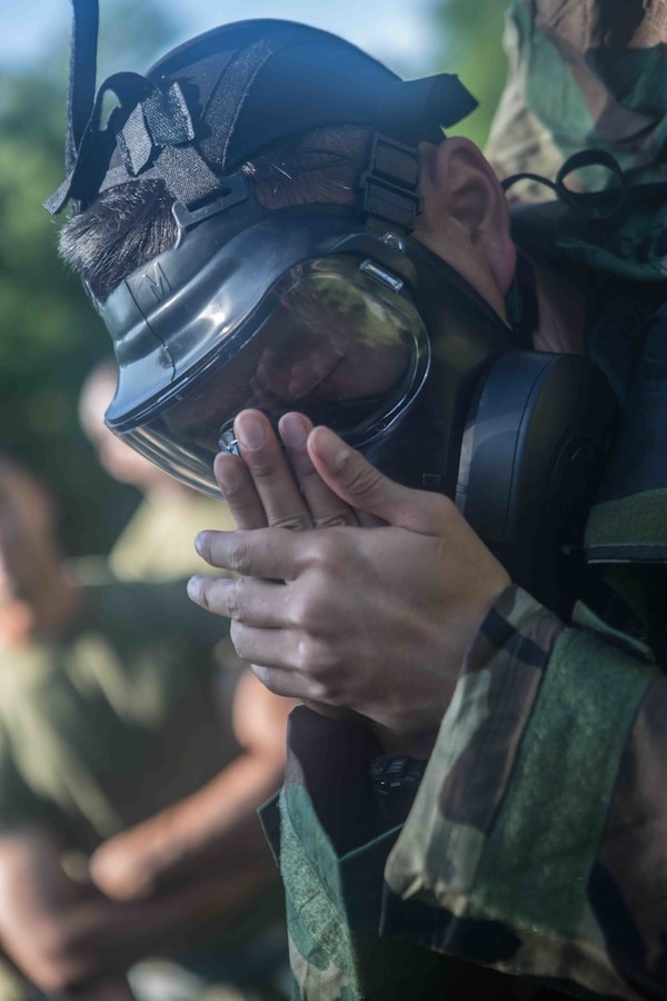 U.S. Marine Corps Lance Cpl. Brian Nguyen, a digital wideband repairman with Marine Wing Communications Squadron 48, Marine Air Control Group 48, 4th Marine Aircraft Wing, demonstrates how to properly seal a gas mask at Joliet Army Training Area, Elwood, Ill., July 15, 2019. MWCS-48 is conducting exercises ranging from rifle and pistol qualifications to land navigation to meet annual training requirements, as well as increase occupational proficiency. (U.S. Marine Corps photo by Lance Cpl. Preston L. Morris)