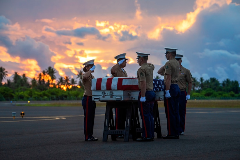 Marines salute a casket draped in American flag.