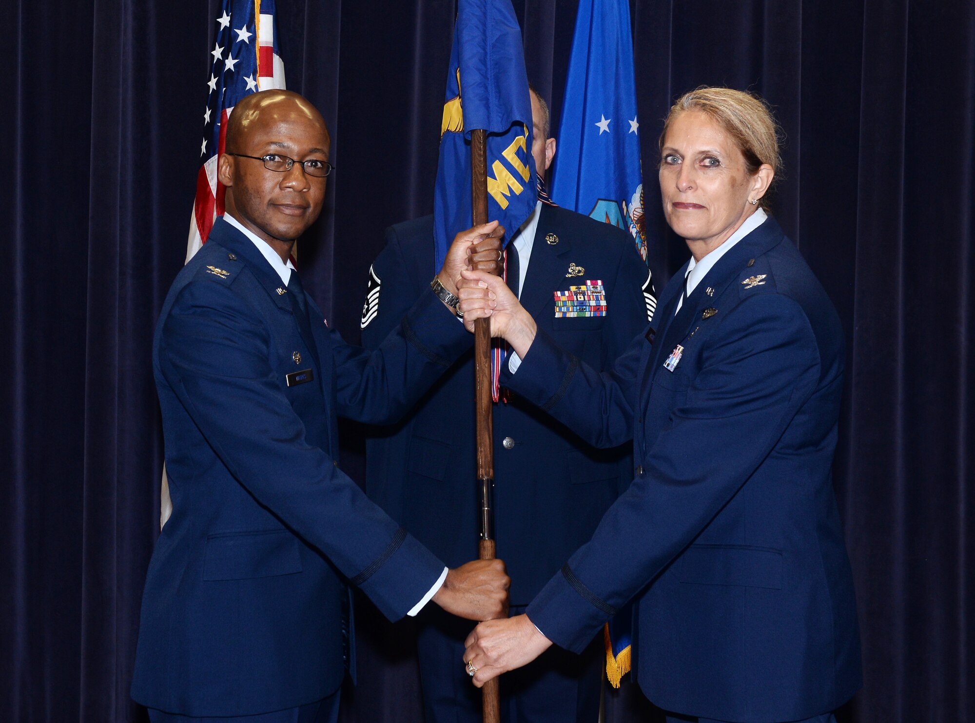 Col. Gavin Marks, 55th Wing commander, passes the 55th Medical Group guidon to Col. Julie Ostrand, during the 55th Medical Group Change of Command ceremony July 11, 2019, inside the 557th Weather Wing auditorium at Offutt Air Force Base, Nebraska. Osrand assumed command from Col. Judy Stoltmann who is retiring soon from the Armed Forces.