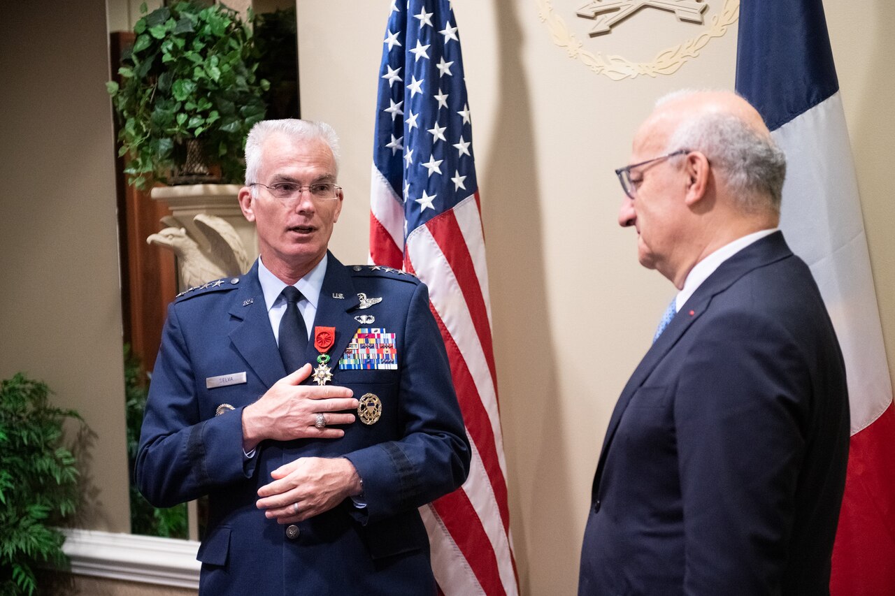A decorated airman stands with his hand on chest after receiving a medal.