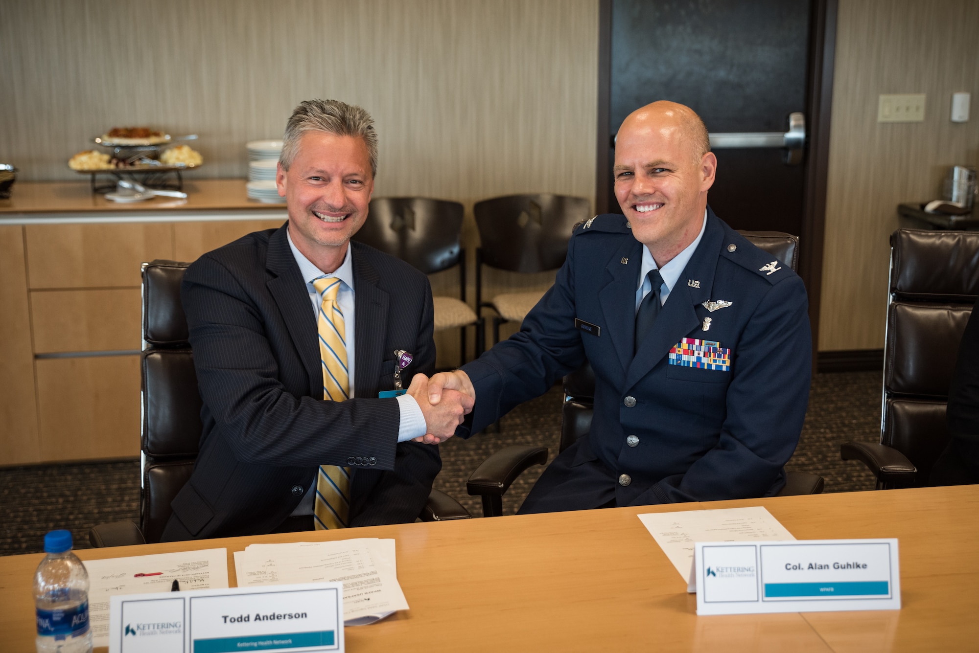 Todd Anderson, executive vice president for Kettering Health Network, and Col. (Dr.) Alan Guhlke, chair, En route Care Training Department at USAFSAM, shake hands after signing a training affiliation agreement July 15 authorizing medical personnel from the USAFSAM to partner together with Kettering Health Network to enhance the readiness of Air Force medical service personnel. (U.S. Air Force photo/Richard Eldridge)