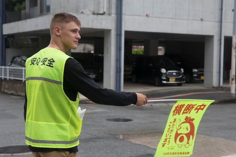 U.S. Marine Corps Lance Cpl. Timothy, observes traffic while conducting crossing guard duty July 18, 2019. Cross guard volunteer opportunities are one of the multiple tasks   Marines on camp guard duty partake in.