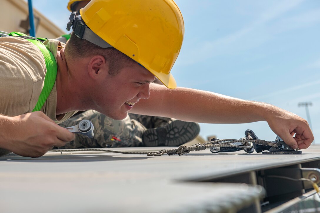 An airman uses tools on the ground.