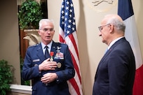 A decorated airman stands with his hand on chest after receiving a medal.