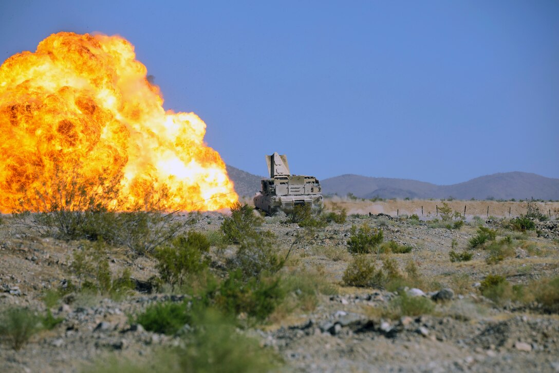 A large fire next to a military vehicle.