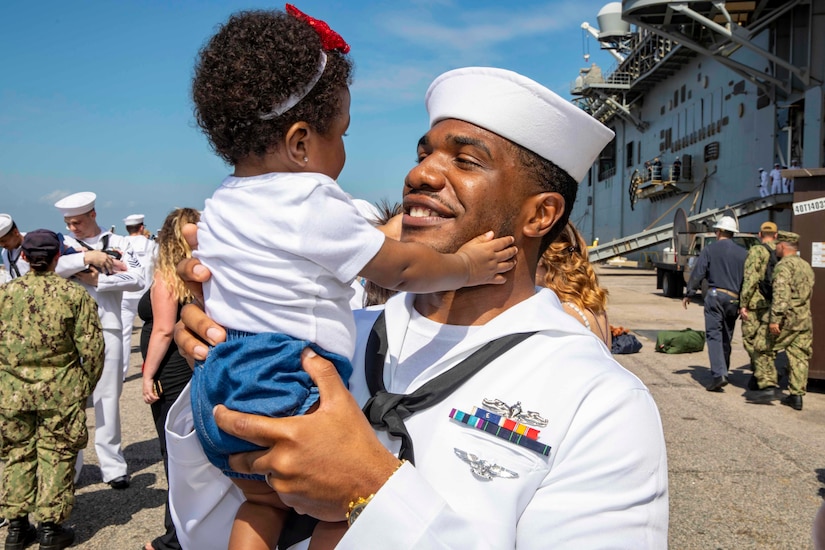 A sailor holds a child.