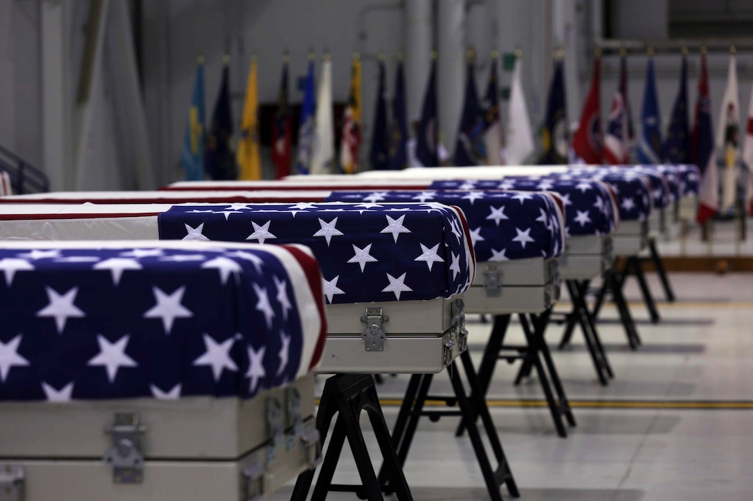 A group of flag-draped caskets sit in a building.