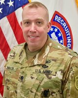 Photo of Lt. Col. Martin J. DeBock, Albany Recruiting Battalion Commander in front of an American and recruiting flag.