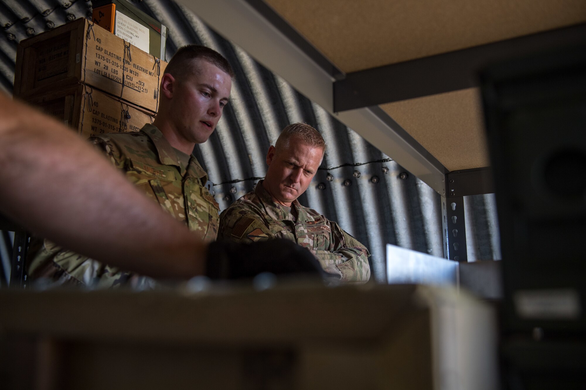 U.S. Air Force Airman 1st Class Thomas Knight, 325th Maintenance Squadron stockpile surveillance crew chief, shows Col. Brian Laidlaw, 325th Fighter Wing commander, how munitions are organized at Tyndall Air Force Base, Florida, July 17, 2019.