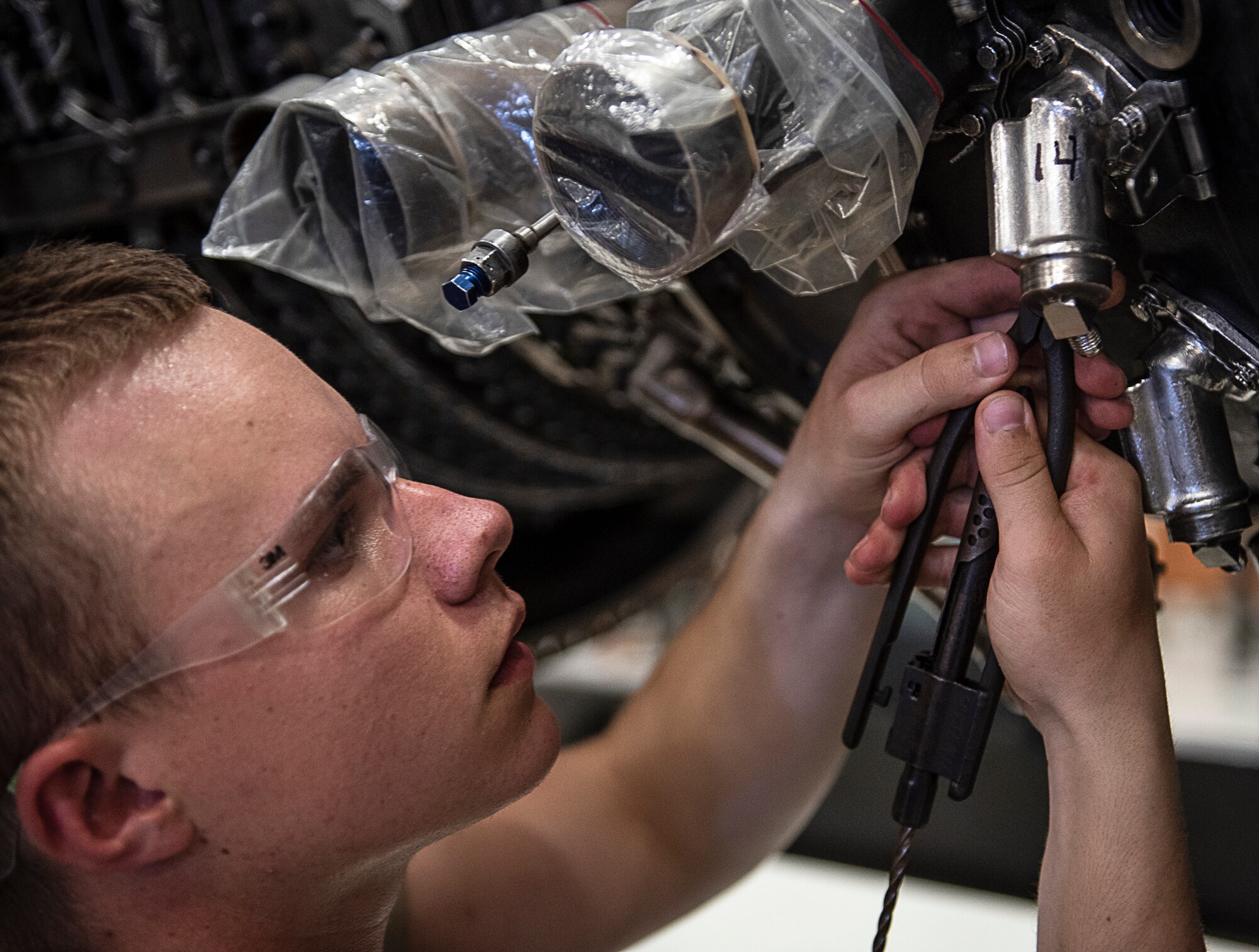 Airman 1st Class Jeremiah Butler, 361st Training Squadron aerospace propulsion apprentice course student, removes safety wires from an F110 turbine engine at Sheppard Air Force Base, Texas, July 18, 2019. Butler is a native from St. Louis, Missouri, and is now attending technical training at Sheppard. In this block he learns how to remove and re-install the fuel nozzle section of the engine. (U.S. Air Force photo by Airman 1st Class Pedro Tenorio)