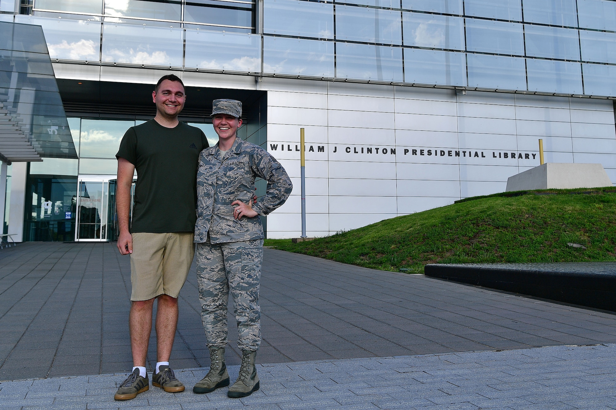 An Airman stands next to her husband in front of the library she will be interning at.