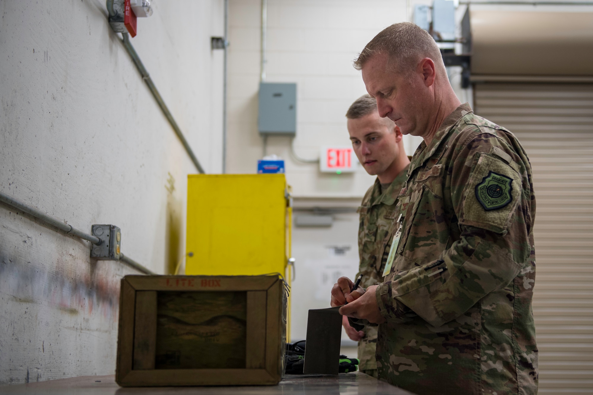 (Right) U.S. Air Force Col. Brian Laidlaw, 325th Fighter Wing commander, ‘shadows’ U.S. Air Force Airman 1st Class Thomas Knight, 325th Maintenance Squadron stockpile surveillance crew chief, and labels a box of munitions for inspection at Tyndall Air Force Base, Florida, July 17, 2019.