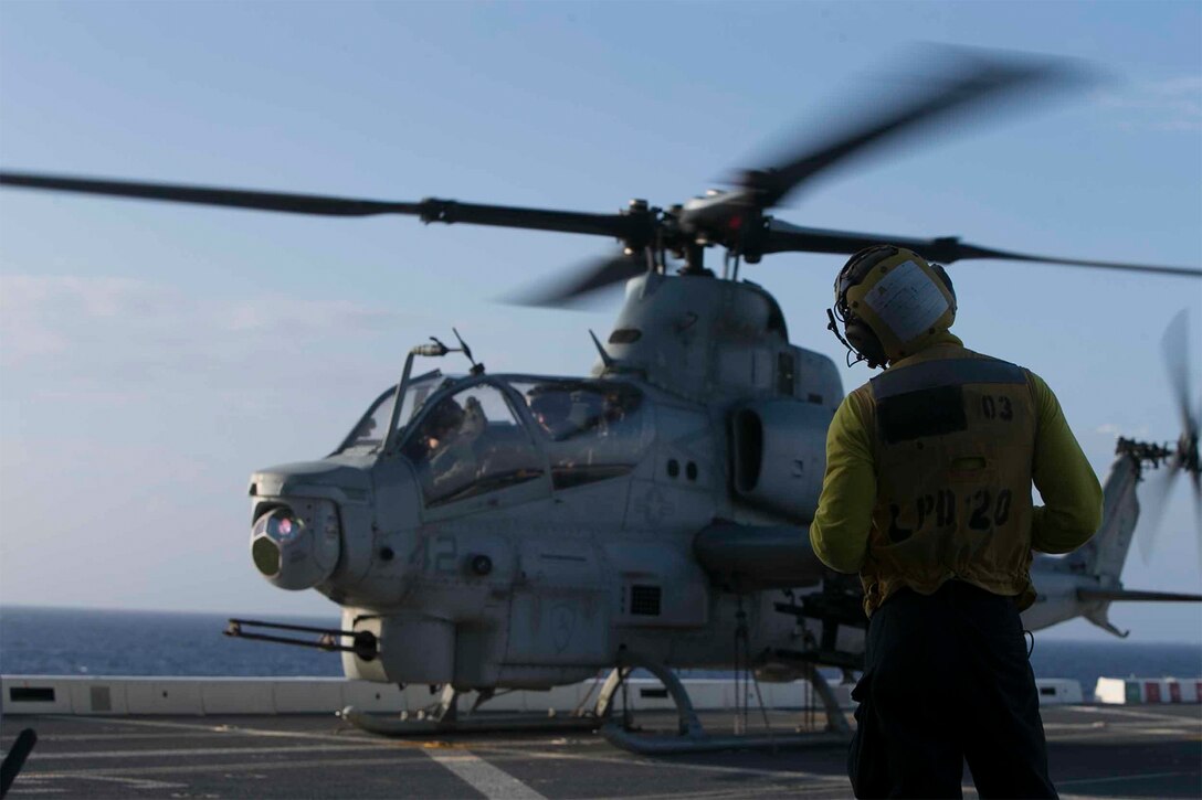 Helicopter whirls on ship at sea.