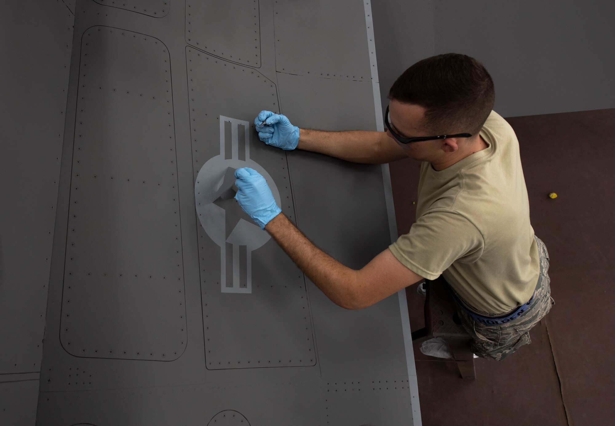 U.S. Air Force Airman 1st Class Holden Nieman, 20th Equipment Maintenance Squadron aircraft structural maintainer, peels a stencil off the side of an F-16CM Viper at Shaw Air Force Base, South Carolina, June 20, 2019.