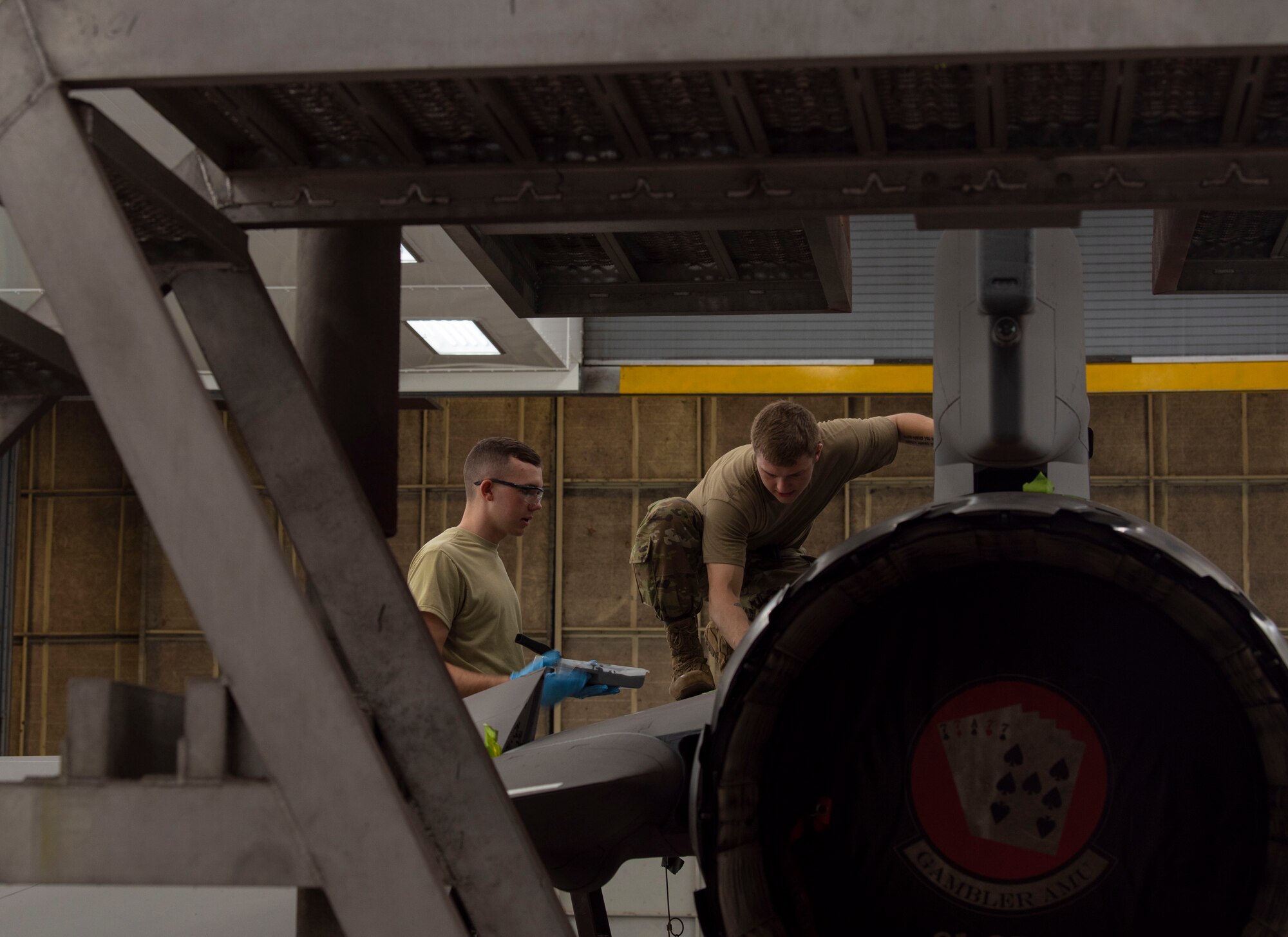 U.S. Air Force Airman 1st Class Holden Nieman and Senior Airman Daniel Meadows, 20th Equipment Maintenance Squadron aircraft structural maintainers, work together to paint a decal on the side of an F-16CM Viper at Shaw Air Force Base, South Carolina, June 20, 2019.